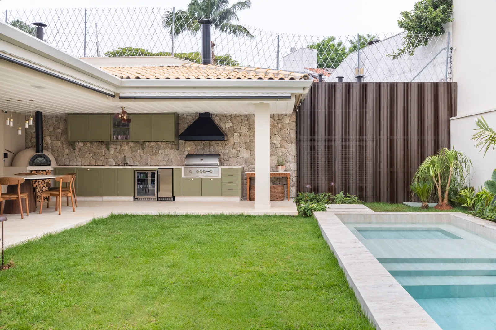 Quintal com piscina de travertino e área gourmet, por Dan Barros