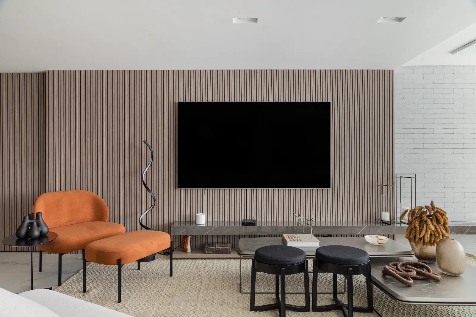 Painel ripado da TV com chaise laranja e tijolinho branco, por Dan Barros