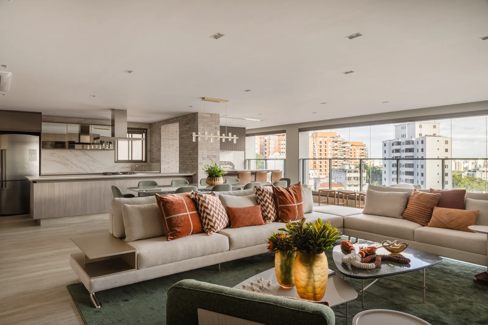 Living com vista da cidade e cozinha integrada ao fundo, por Dan Barros